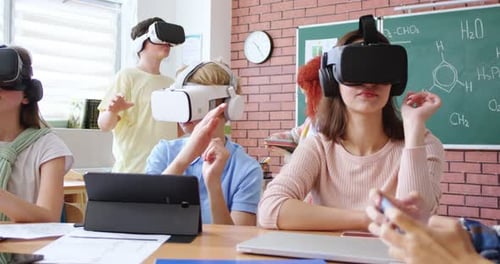 Group of Happy Young Pupils of School Sitting in Classroom and Using Virtual Reality Headsets