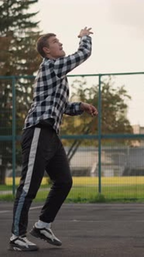 Man Throwing Volleyball to Slam in Outdoor Court with Green Field Background