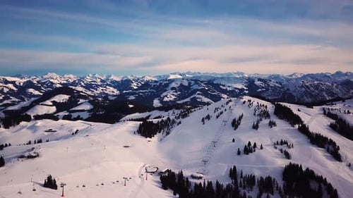 Snowy mountains in low clouds and blue sky at sunset in winter. Panoramic landscape with beautiful s