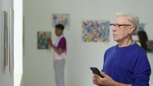 Man Taking Picture of Artwork in Gallery