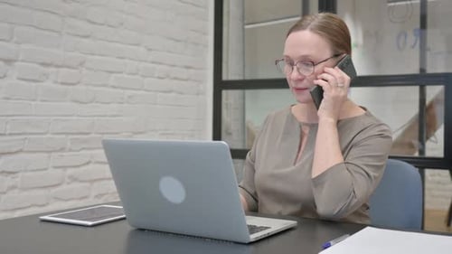 Woman Working at Desk Talking on Phone