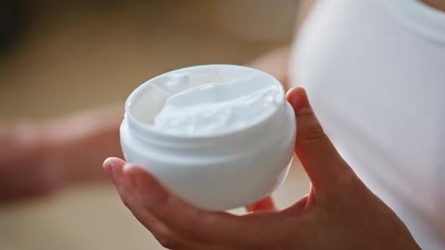 Woman Takes Cream from Jar for Skincare Routine