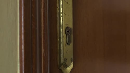 Hand with a key closing the house door. Close up. Locking or unlocking the door.