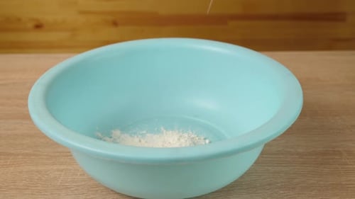Flour Being Poured into Light Blue Bowl