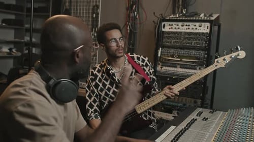 Musicien avec guitare et opérateur enregistrant de nouvelles musiques en studio