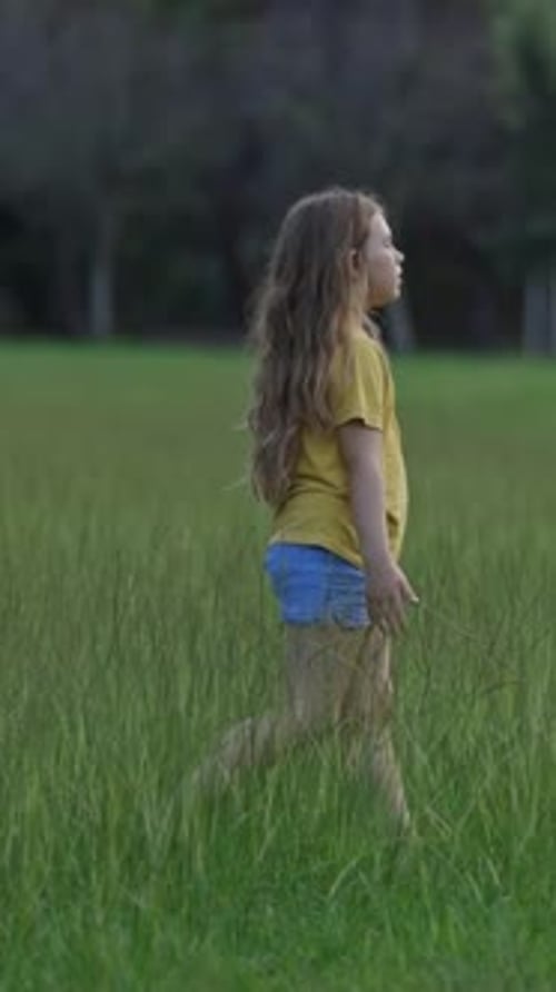 Young Girl Joyfully Walking Through a Sunlit Field of Tall