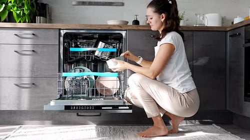 Woman Loading Dishes Into Modern Dishwasher