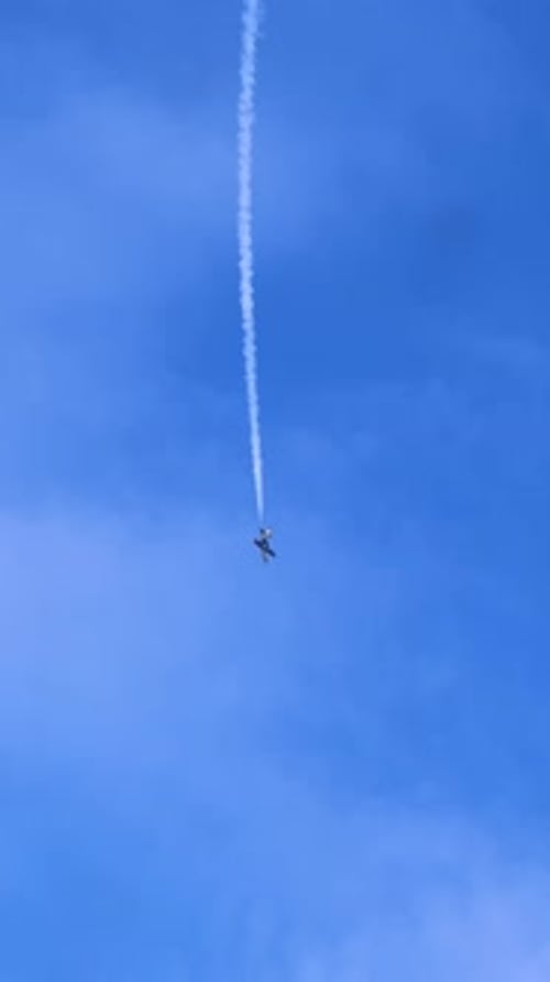 Small Plane Flying Creating Smoke Trail in Blue Sky