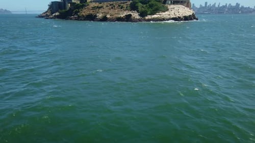 Gimbal tilting up shot from the San Francisco Bay to the backside of Alcatraz Island on a moving boa