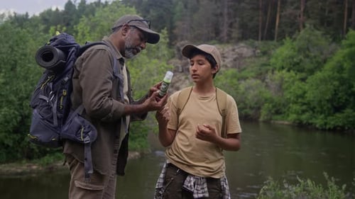Father Sprays Insect Repellent on Teen's Arm Outdoors