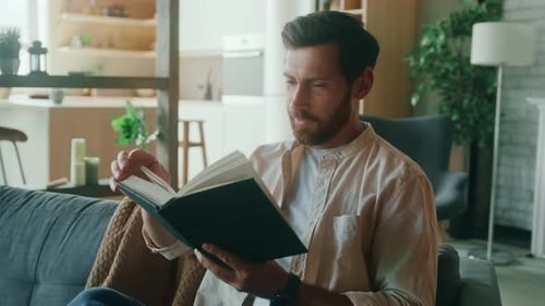 Man Reads a Book on Couch at Home