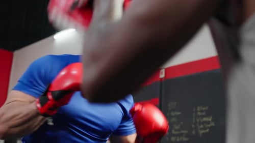African american fitness trainer support sportsman doing boxing in gym.