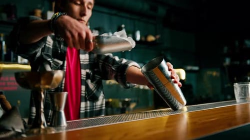 Bartender Adding Ice to Cocktail Shaker in Bar