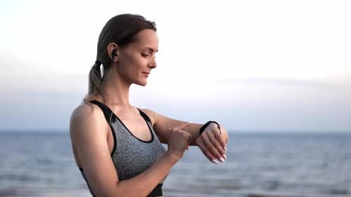 Smiling Fitness Woman Checking Body Care Workout Data Smartwatch Healthy Lifestyle at Sunset Beach