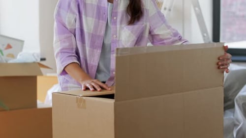 Woman Packing Cardboard Box for Moving House