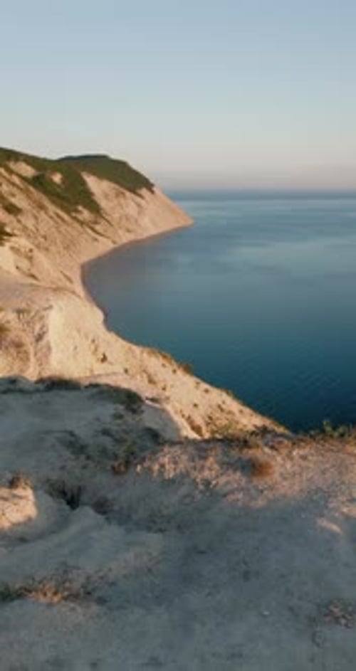 Rocky Coastline with Quiet Sea and Sunset Warm Tones Vertical Footage