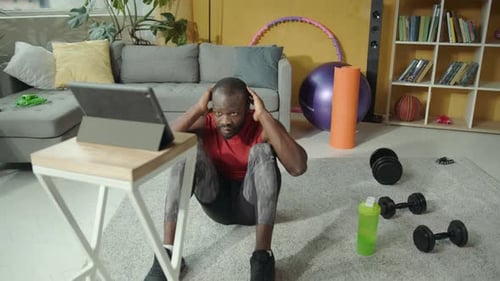 Un homme fait des séances d'entraînement à domicile avec une tablette et un ordinateur portable faisant preuve de détermination
