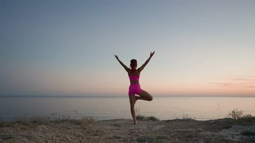Athletic Fitness Woman Doing Yoga on the Background of Sunset Sea and Rocks
