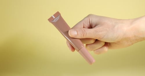 Woman's Hand Holds Cosmetic Product in Studio Setting