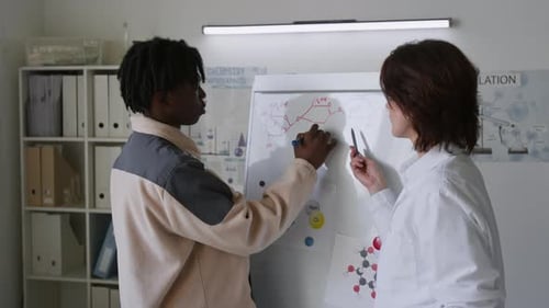 Student and Teacher Discussing Chemical Formula on Whiteboard