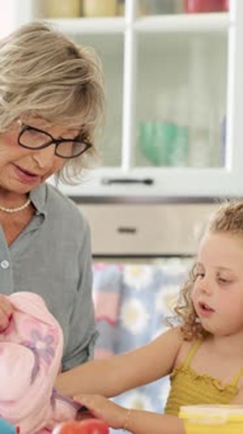 Grandmother Preparing Granddaughter for School in the Kitchen Vertical