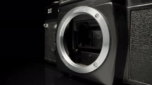 Old SLR, film camera, on a black background.