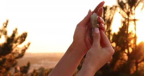 Woman Holding a Crystal Outdoors During Golden Hour