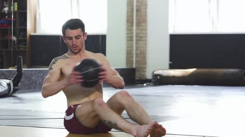 Determined Ripped Male Athlete Intensely Working Out with a Medicine Ball