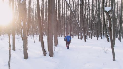 Young Man and Woman Running in Winter Forest at Early