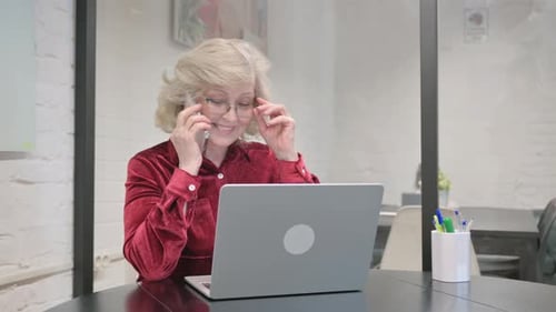 Mature Woman on Phone at Desk with Laptop