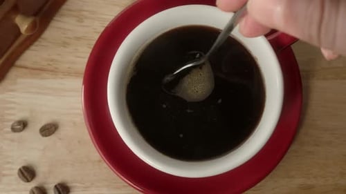 Ansicht von oben auf einen Mann, der Kaffee mit einem Löffel umrührt