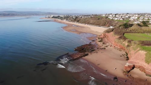 Aerial backwards shot of people walking on a beach at Exmouth Devon England on a sunny weekend