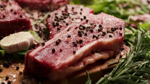 Seasoned Raw Steaks on Wooden Cutting Board