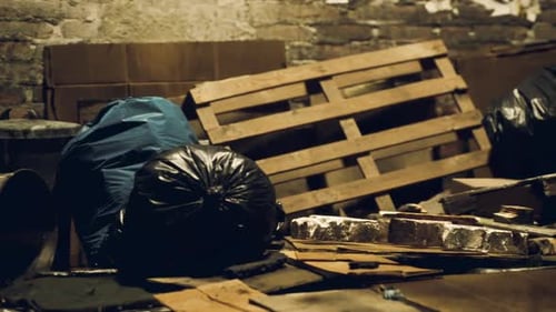 Discarded Materials and Bags Clutter a Dimly Lit Storage Area at Night