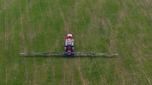 Aerial drone view of agricultural machinery spraying the field and working the land