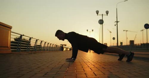 Young Athletic Man Working Out Doing Pushups on a City Street at Sunset