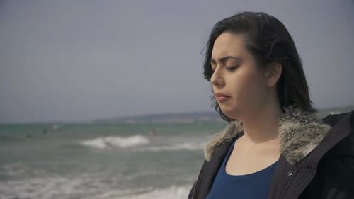 sad depressed young woman contemplating the sea on the beach in windy day