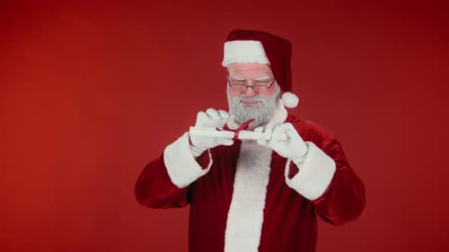 Santa Claus Unrolls Christmas List on Red Background