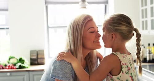 Loving mother and daughter hug and kiss in kitchen