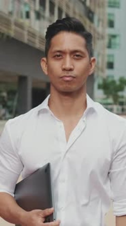 Young Adult Man Holding Laptop in Urban Setting
