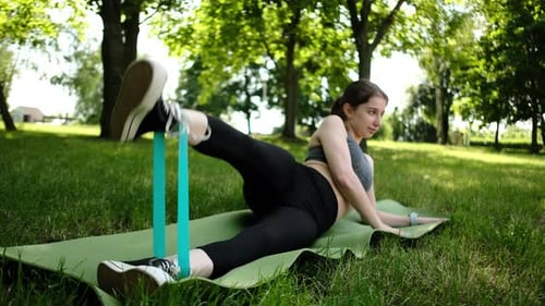 Woman Exercising Legs with Resistance Band in Park