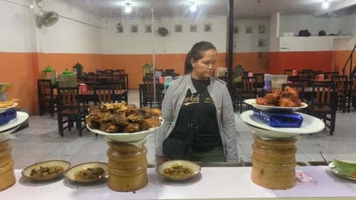 Woman Stands Behind Counter With Plates of Food