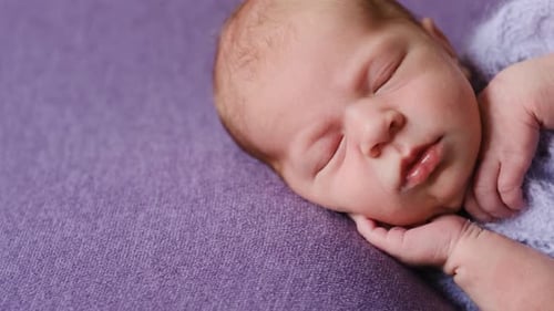 Adorable Newborn Baby Sleeping Peacefully on Purple Blanket