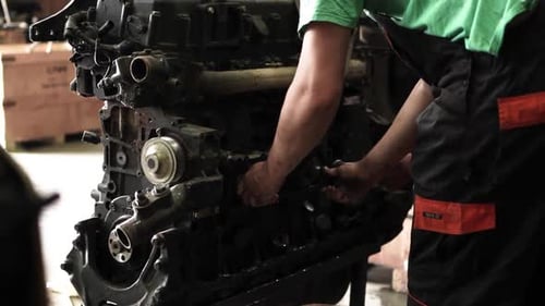 Mechanic Repairing Engine in Industrial Workshop
