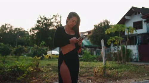 Stylish Young Woman Using Phone at Golden Hour
