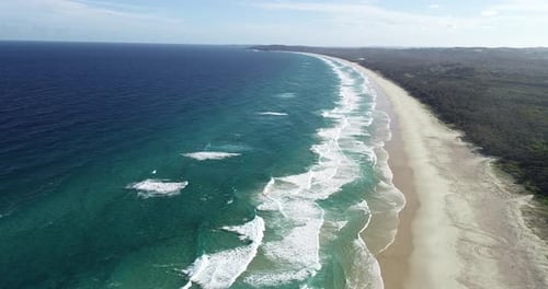 Aerial top view of a white sand beach, waves rolling and nice vegetation. Beautiful drone point of v