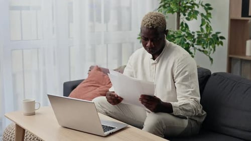 Man Works with Laptop and Documents on Couch