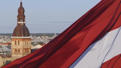 Latvian Flag Waving with Riga Skyline Background