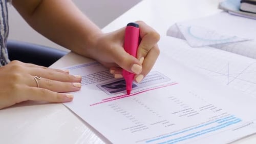 Left-handed Girl Using A Pink Marker In Highlighting Her Homework - Close-up Shot