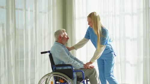 Gentle Nurse Comforting Elderly Man in Wheelchair